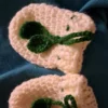 Cream crochet baby mittens with green leaf tie cord