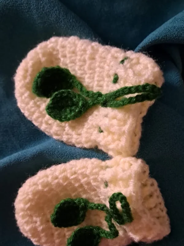 Cream crochet baby mittens with green leaf tie cord