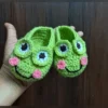 Green crochet frog baby booties with smiling face