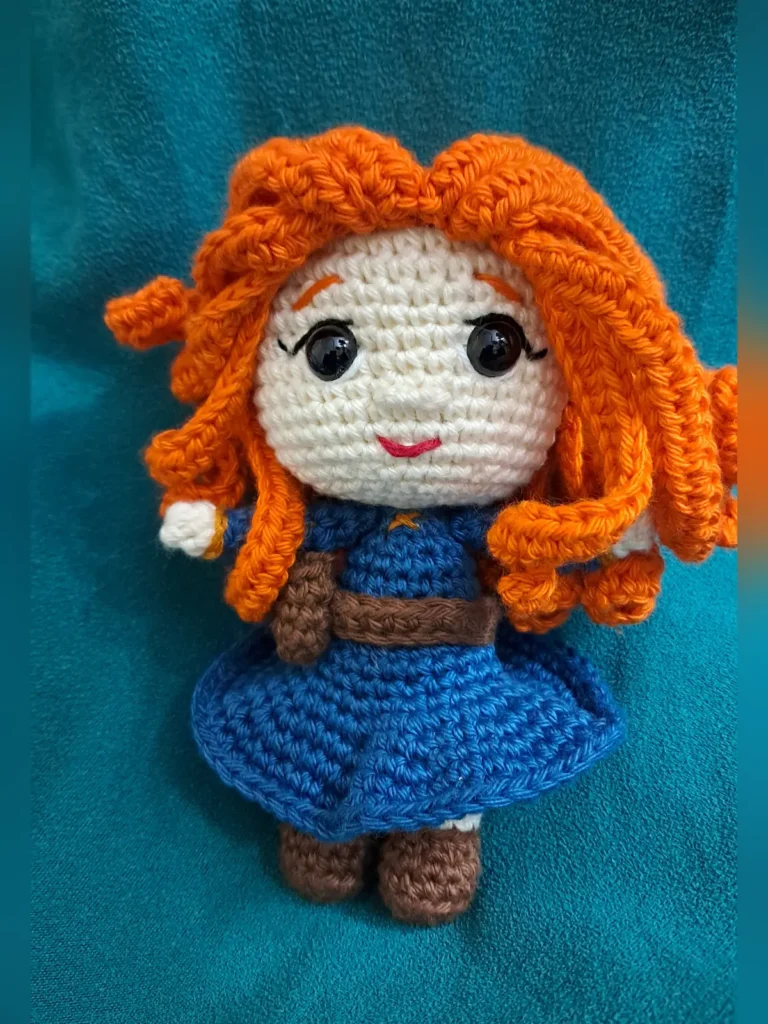 Handmade crochet amigurumi doll with curly red hair and blue dress