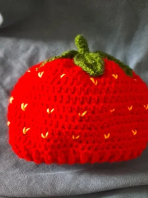 Red crochet strawberry baby cap with green stem