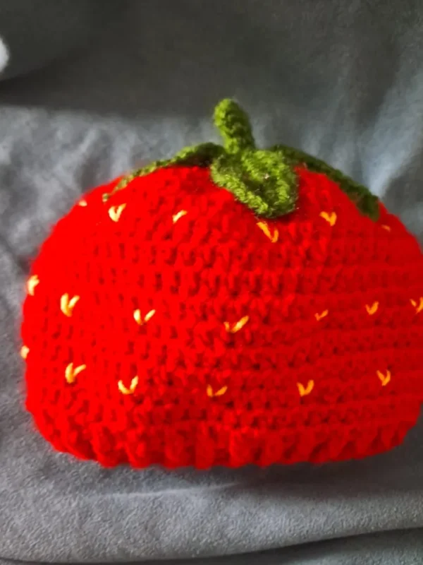 Strawberry Baby Cap, view 1 Red crochet strawberry baby cap with green stem